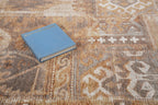 Blue book on tan wool rug with geometric cross pattern and tribal design
