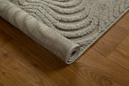 Beige quilted area rug with geometric pattern on wooden floor, corner detail