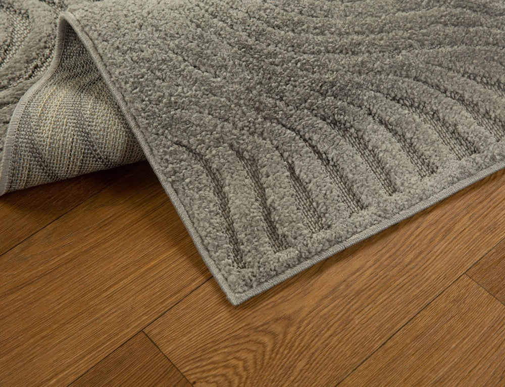 Beige quilted area rug with geometric pattern on wooden floor, corner detail