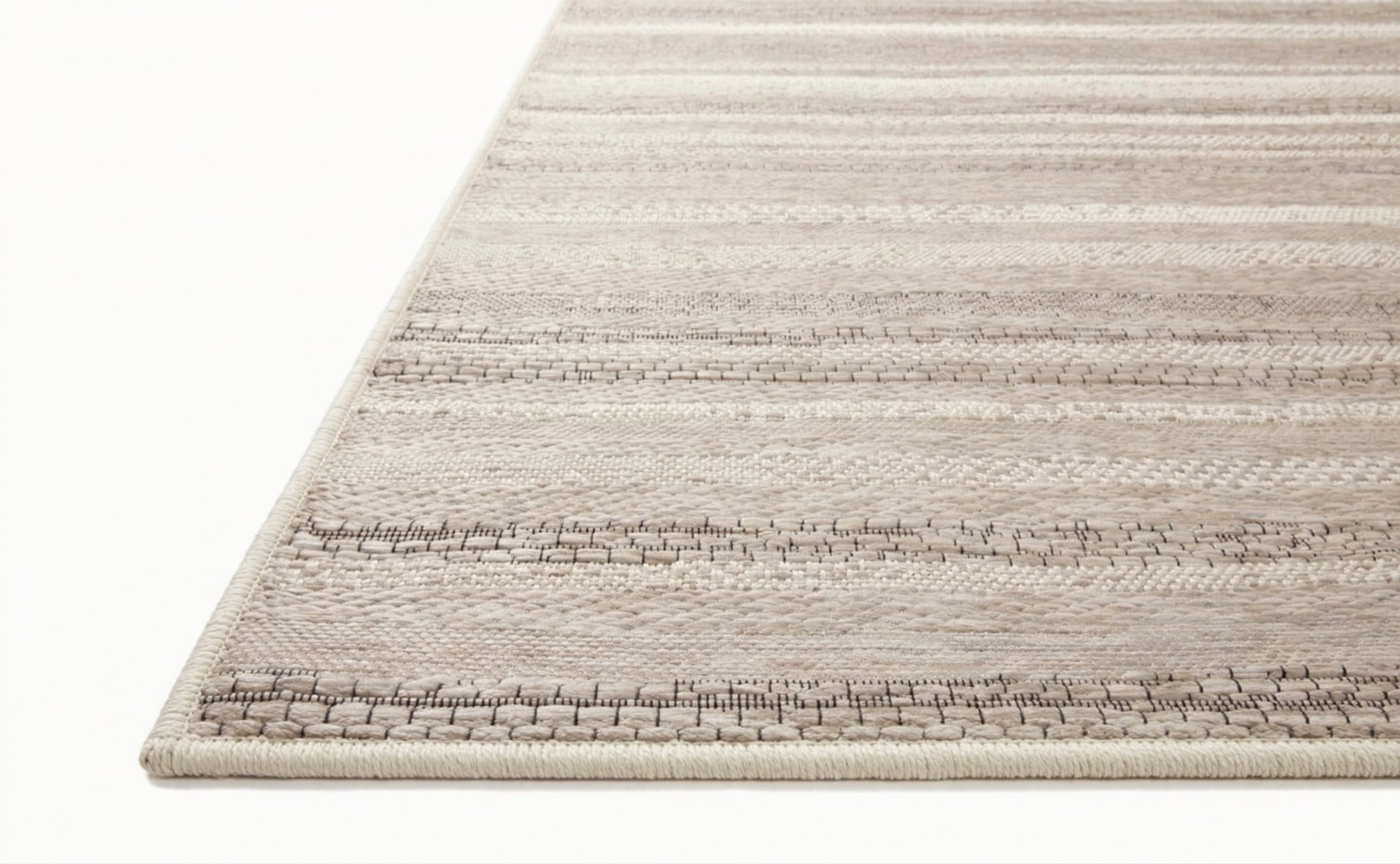 Neutral striped outdoor rug in beige and grey tones on patio