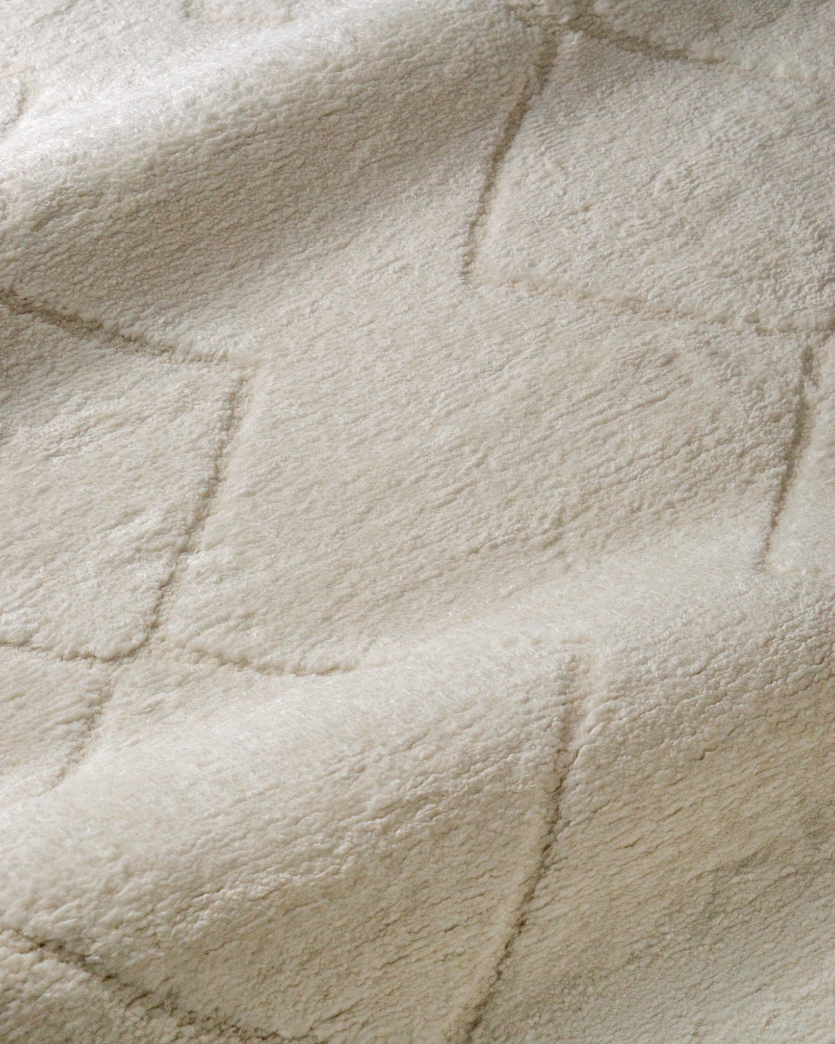 Cream quilted diamond pattern wool area rug with subtle texture