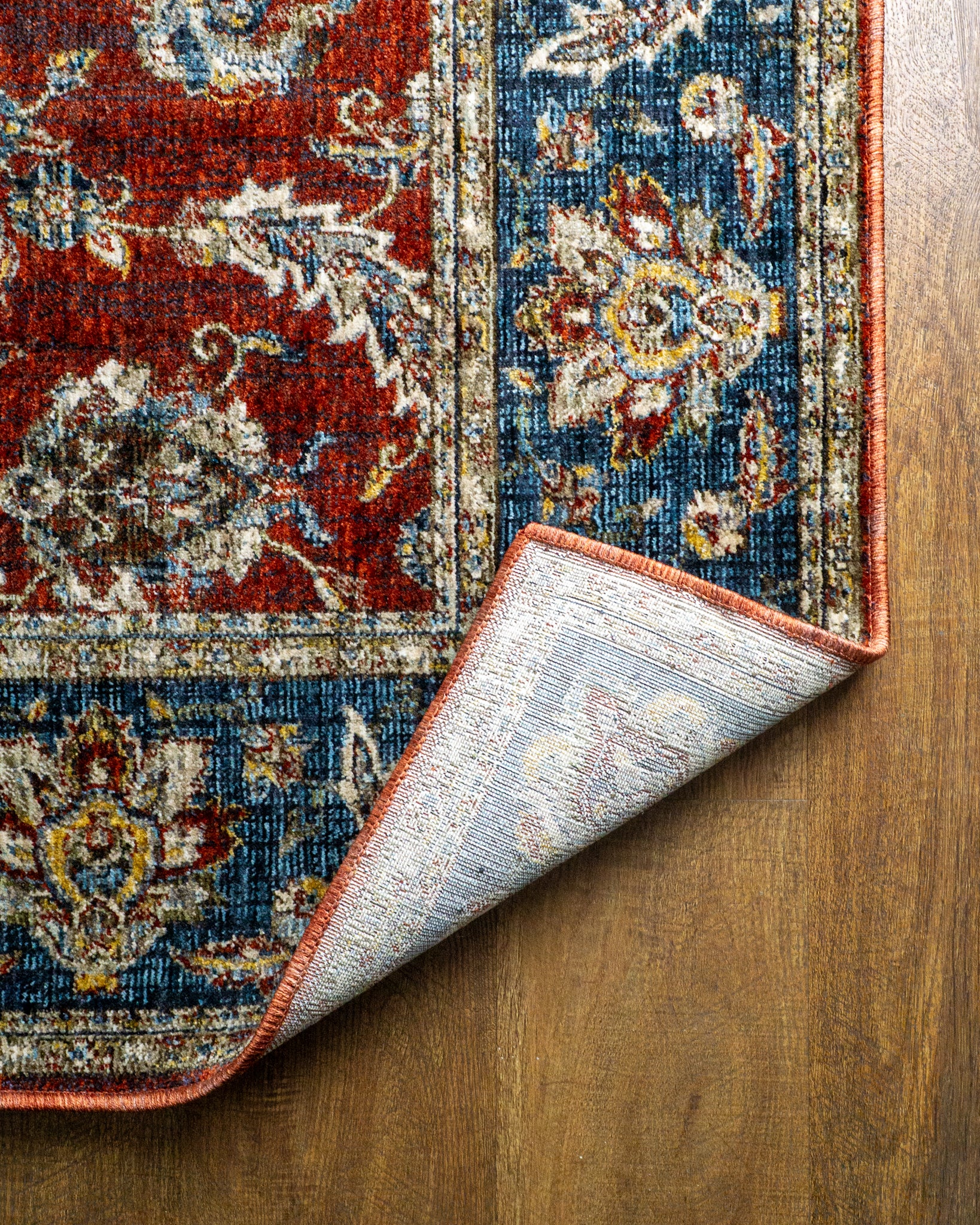 Red traditional rug with ornate floral patterns and blue border design