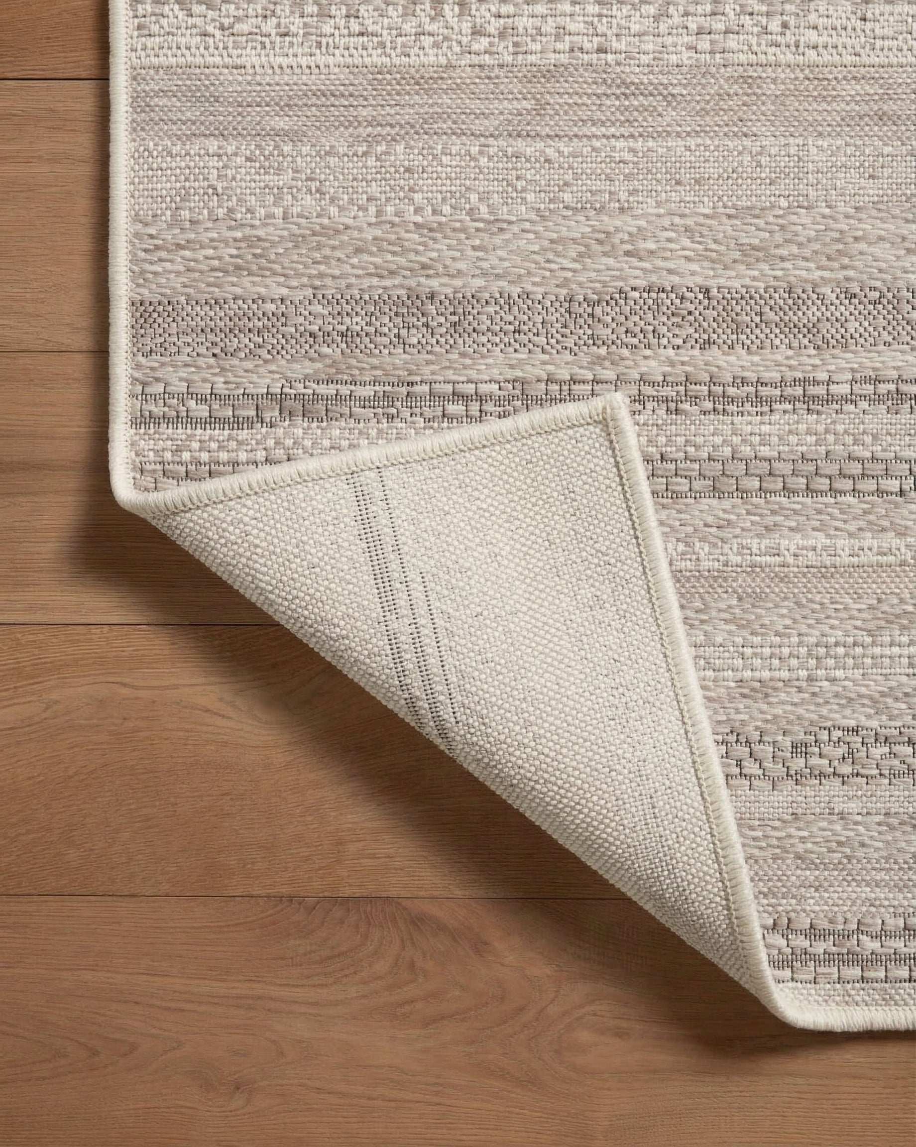 Neutral striped outdoor rug in beige and grey tones on patio