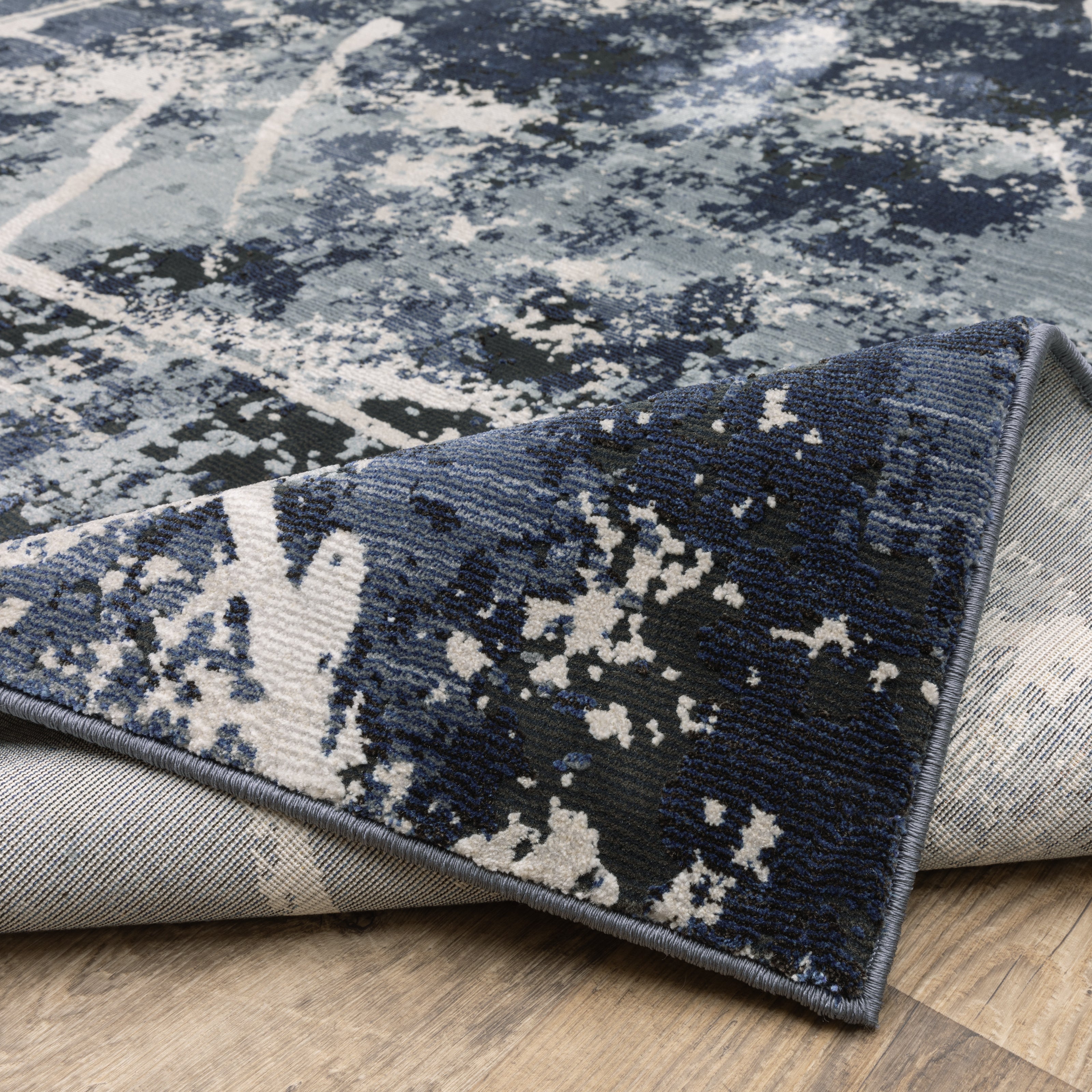 Modern distressed rug with dark navy and grey base, white splatter abstract pattern