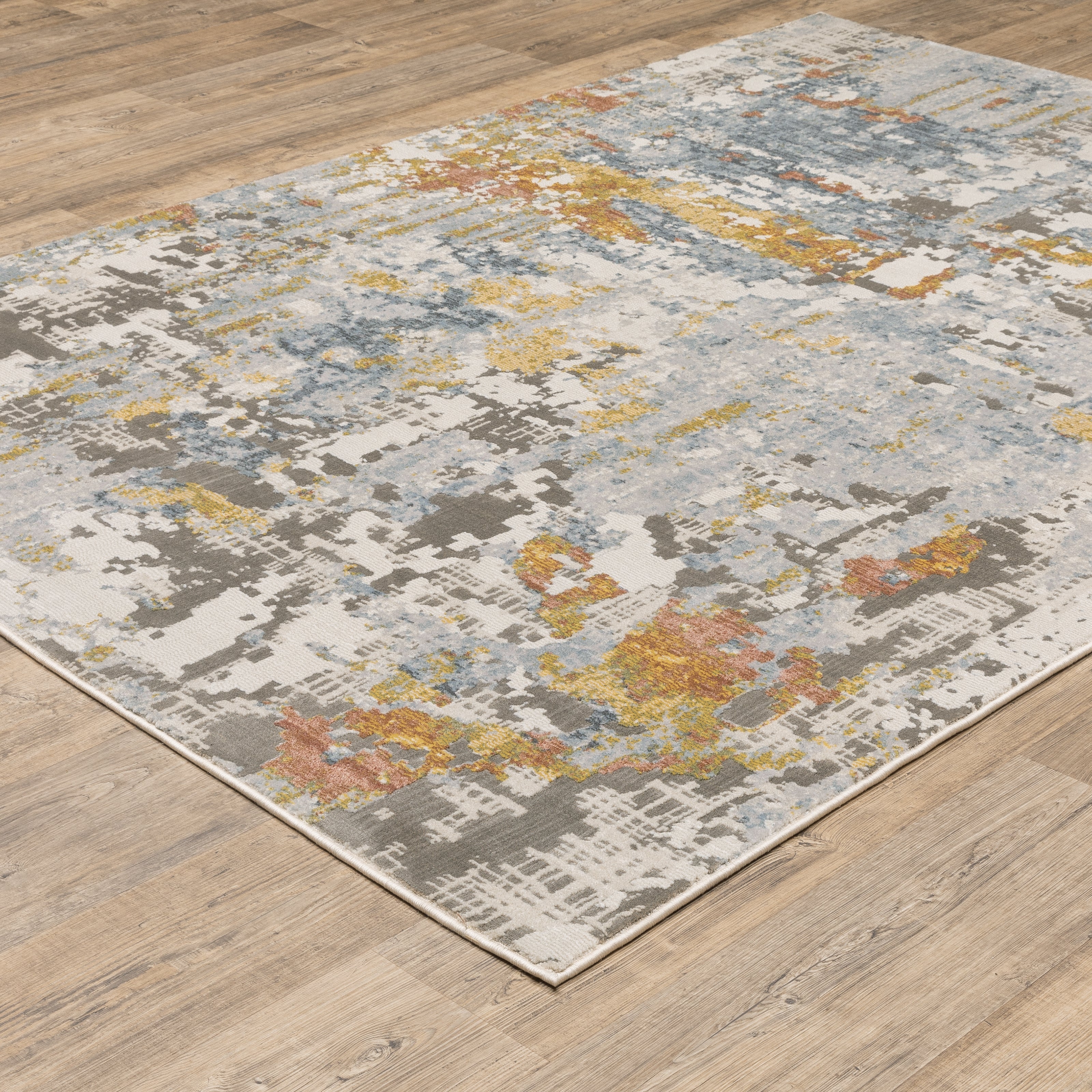 Modern abstract rug with distressed grey, gold, and blue tones featuring architectural patterns
