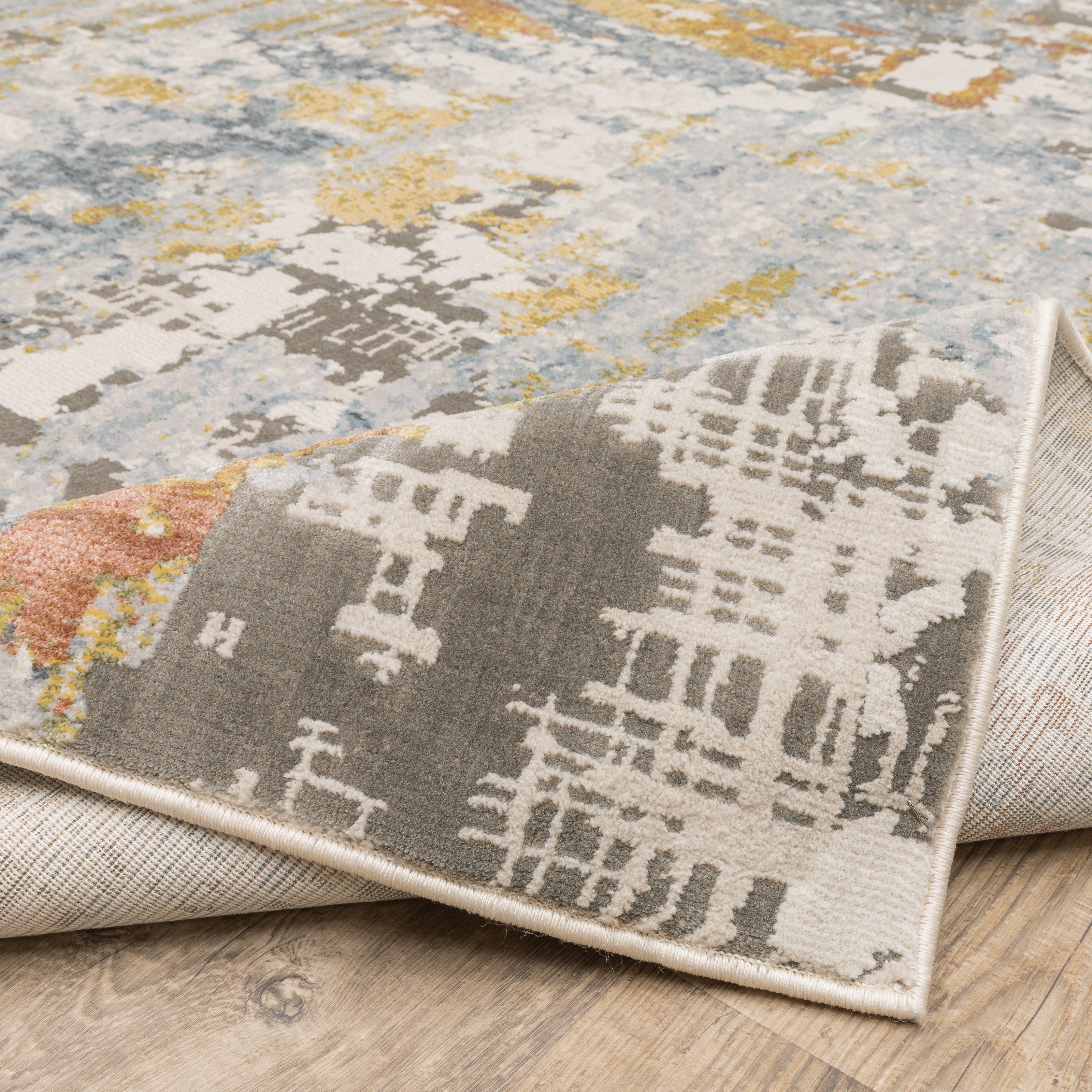 Modern abstract rug with distressed grey, gold, and blue tones featuring architectural patterns