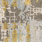 Modern abstract rug with distressed grey, gold, and blue tones featuring architectural patterns