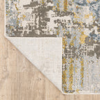 Modern abstract rug with distressed grey, gold, and blue tones featuring architectural patterns
