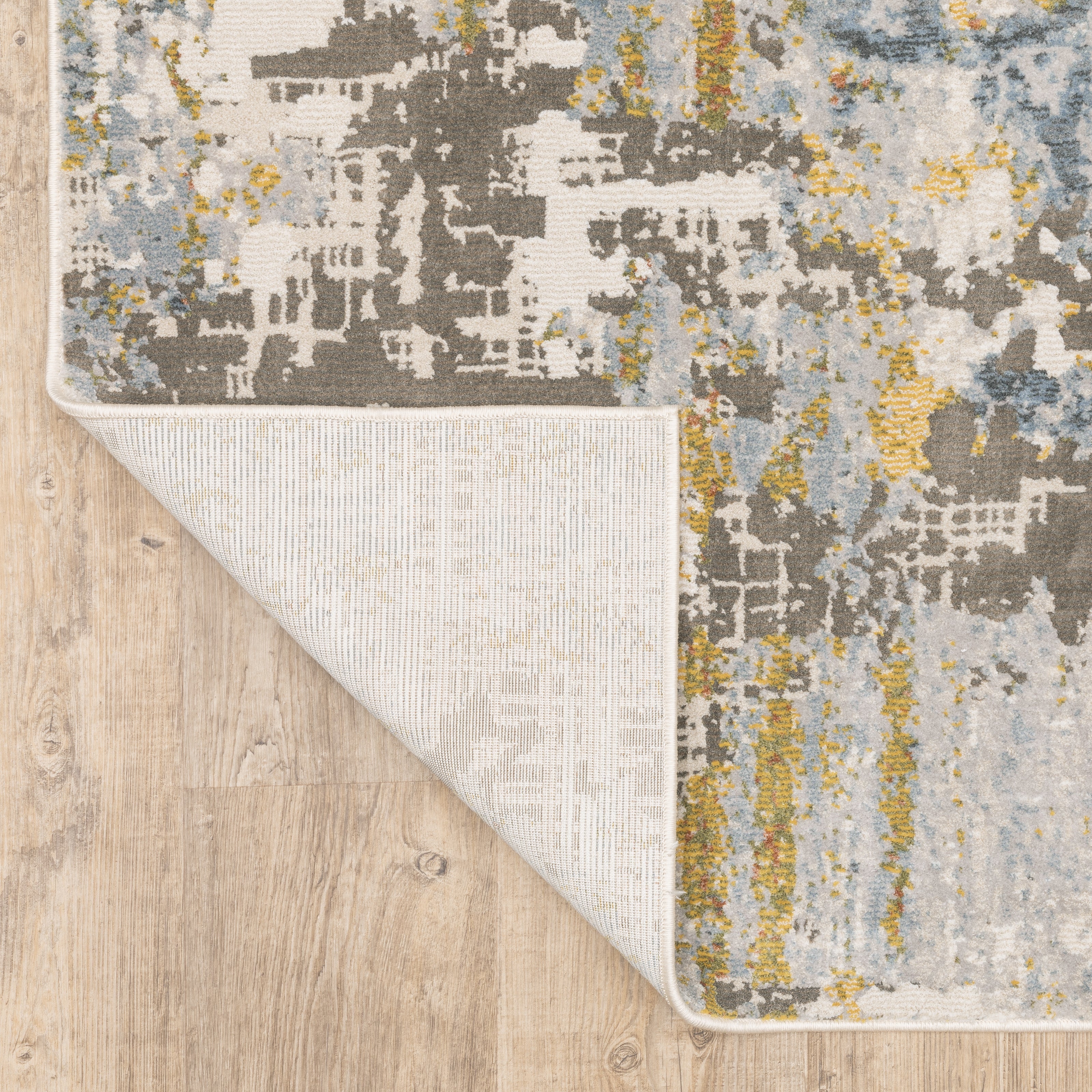 Modern abstract rug with distressed grey, gold, and blue tones featuring architectural patterns