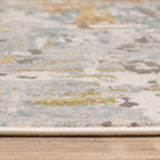Modern abstract rug with distressed grey, gold, and blue tones featuring architectural patterns
