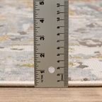 Modern abstract rug with distressed grey, gold, and blue tones featuring architectural patterns