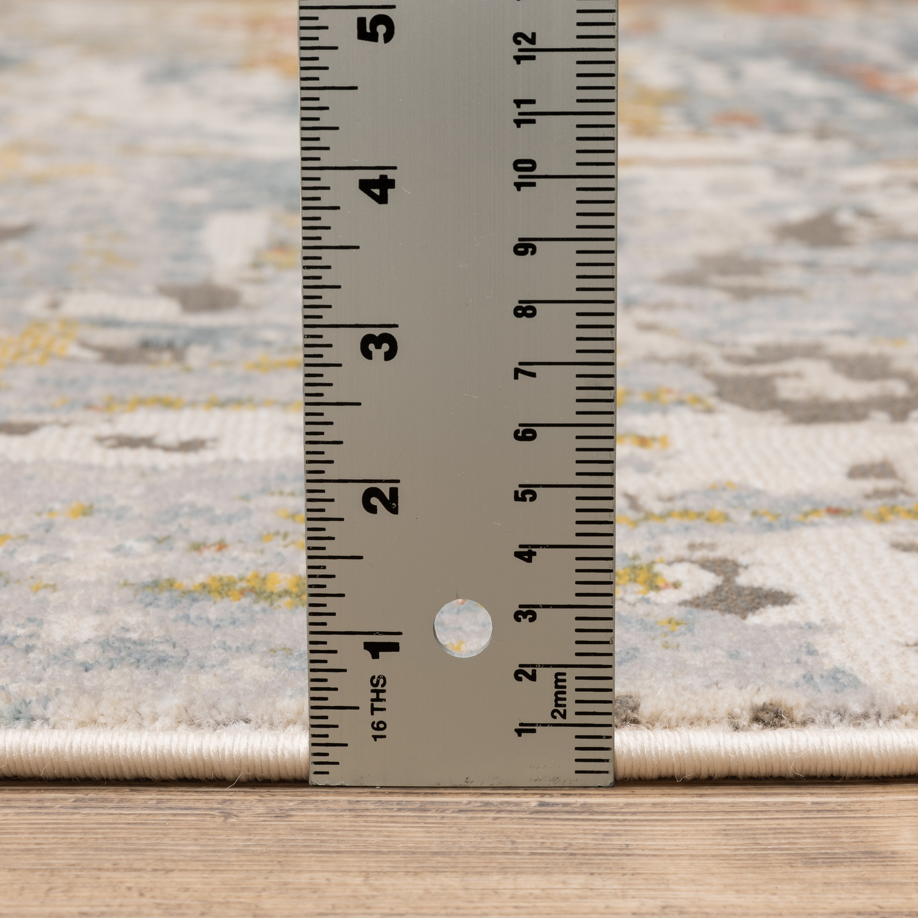 Modern abstract rug with distressed grey, gold, and blue tones featuring architectural patterns