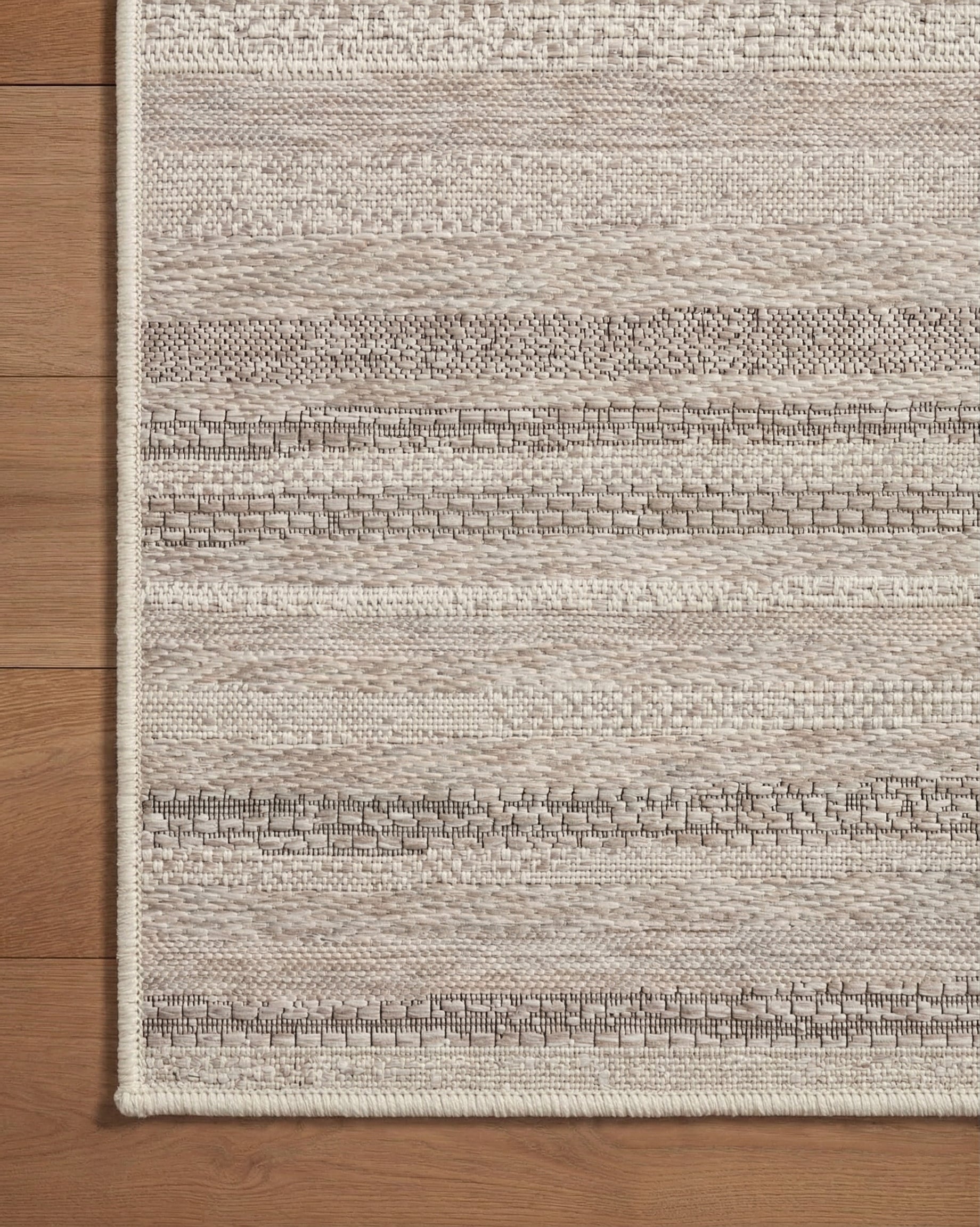 Neutral striped outdoor rug in beige and grey tones on patio