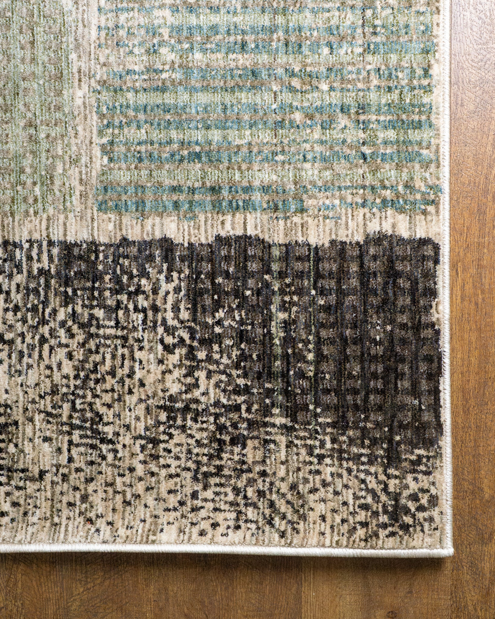 Modern geometric patchwork rug in green, black, and neutral tones with textured weave