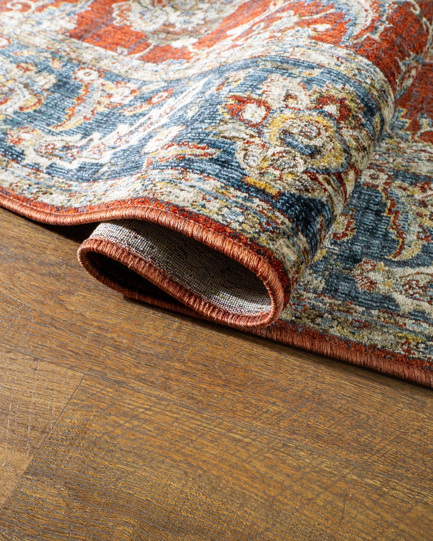 Red traditional rug with ornate floral patterns and blue border design