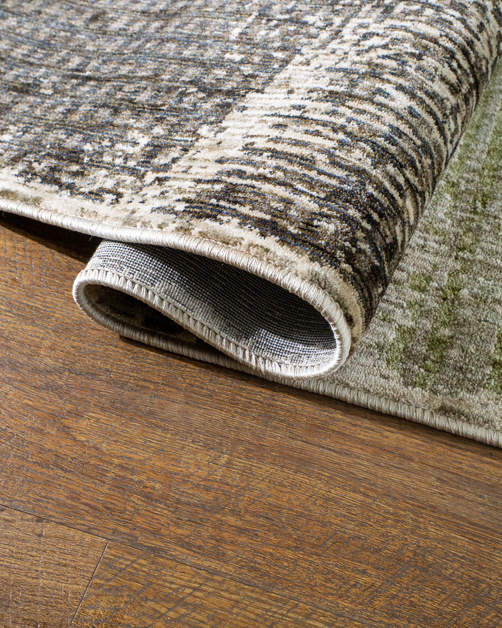 Modern geometric patchwork rug in green, black, and neutral tones with textured weave