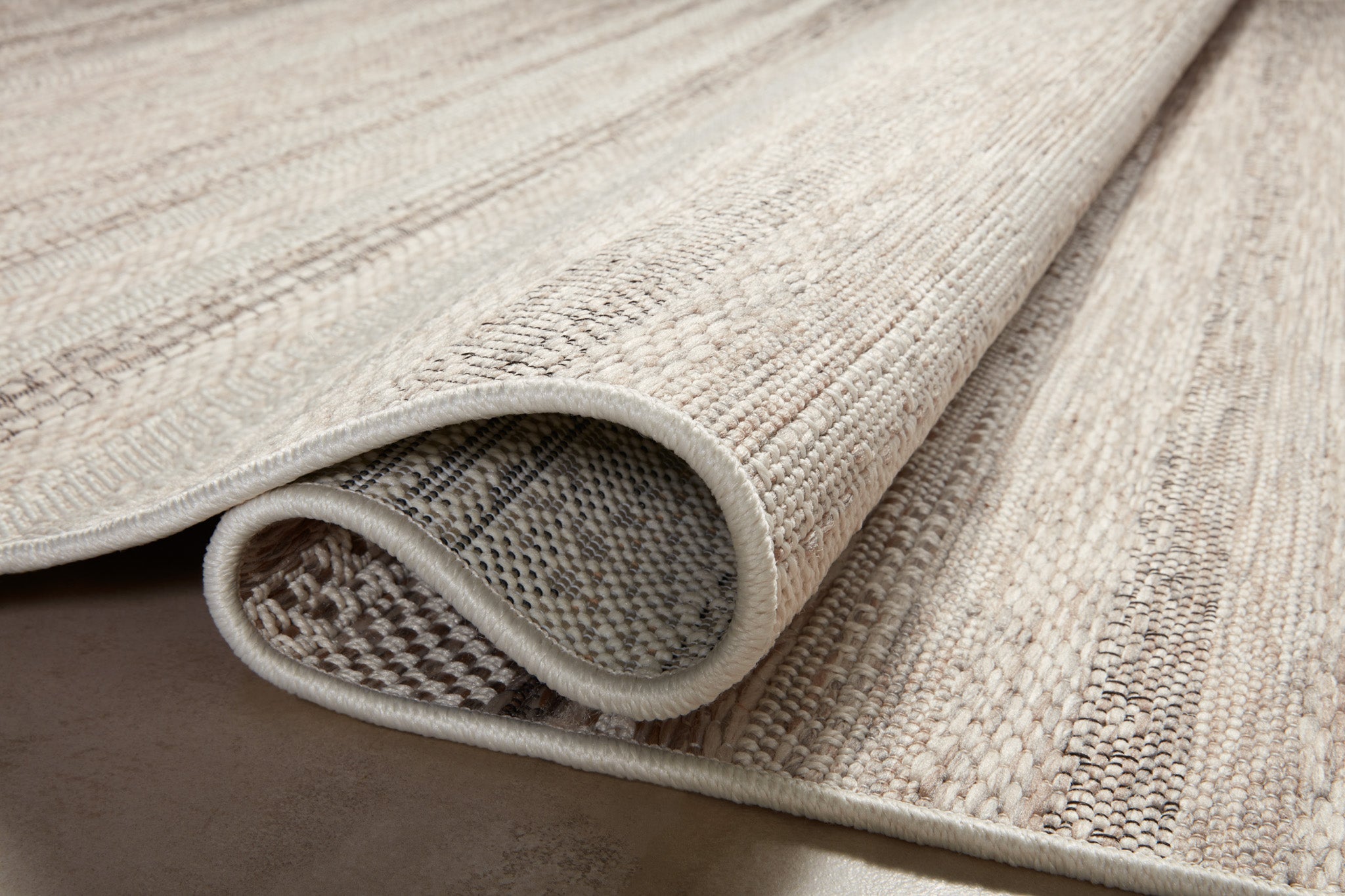 Neutral striped outdoor rug in beige and grey tones on patio