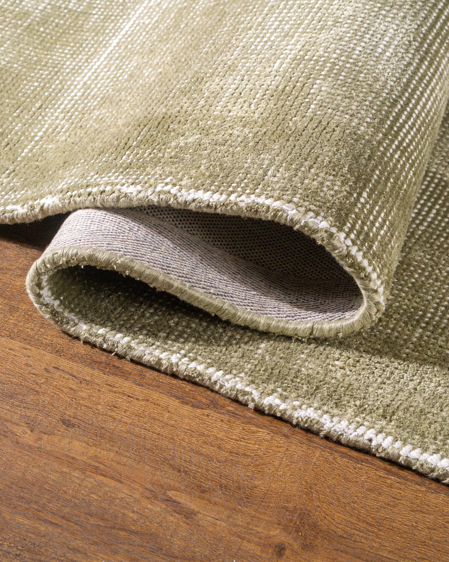 Sage green velvet rug with subtle texture and solid mottled pattern