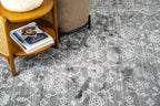 Charcoal grey distressed rug with intricate ivory floral medallion pattern and borders