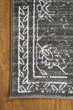 Charcoal grey distressed rug with intricate ivory floral medallion pattern and borders
