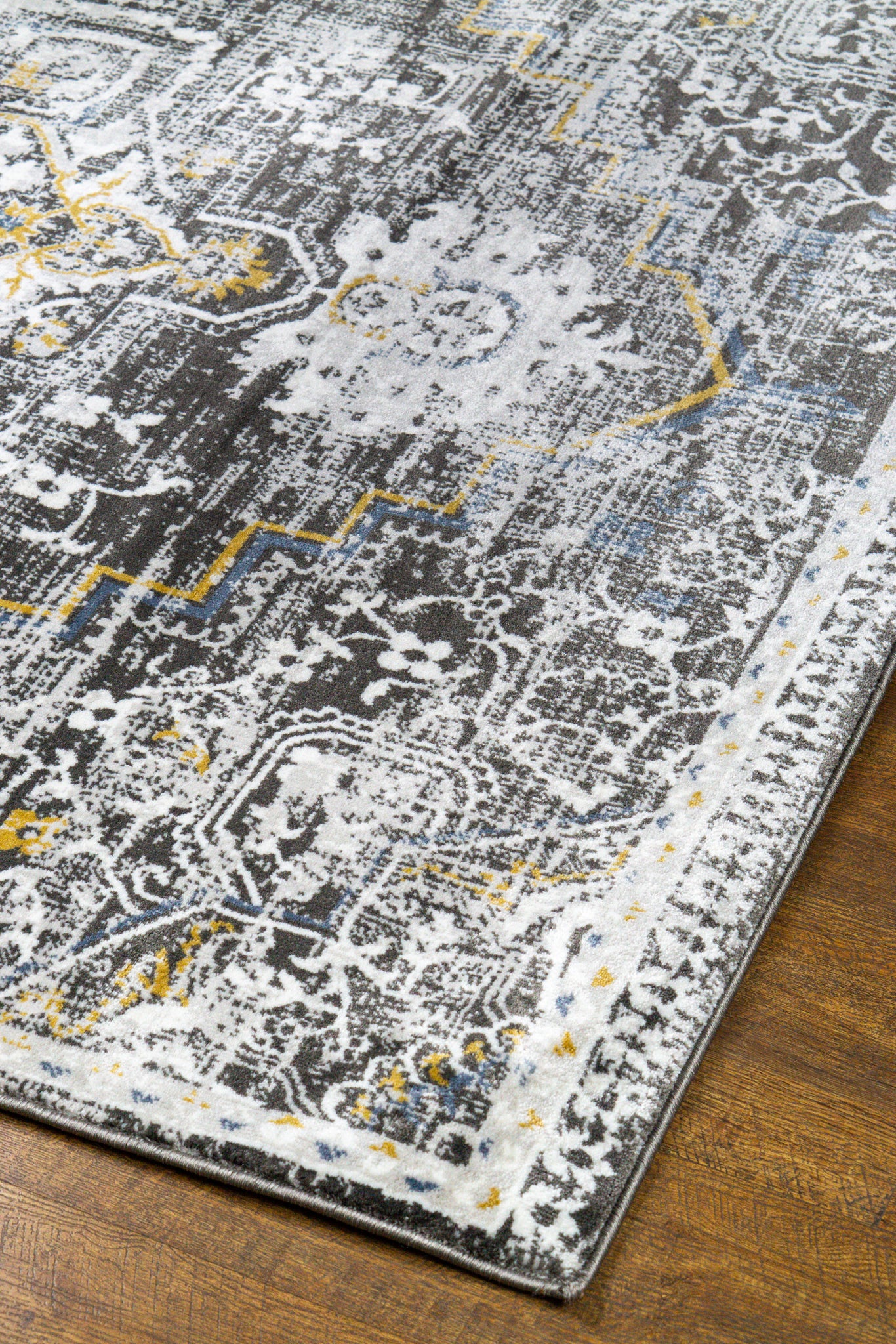 Vintage-style rug with ornate geometric patterns in gray, gold, and black tones
