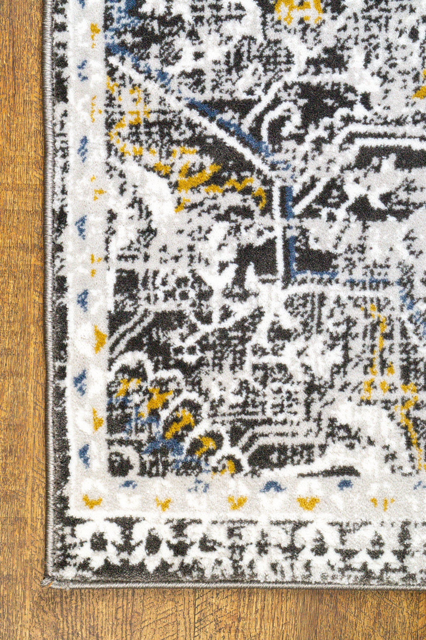 Vintage-style rug with ornate geometric patterns in gray, gold, and black tones