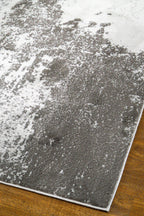 Distressed grey and white rug with abstract speckled texture and worn finish