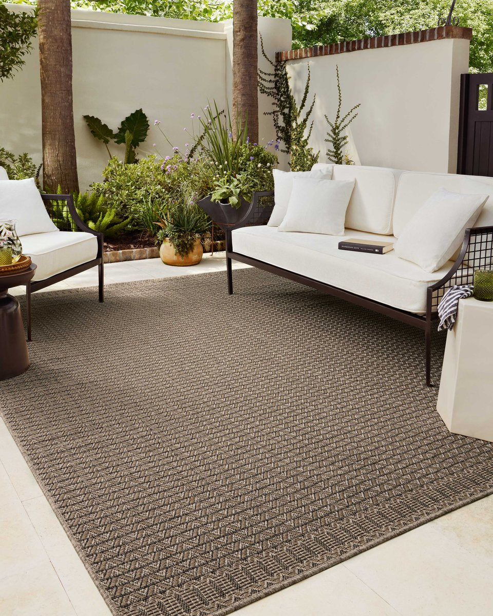 Tan and brown geometric patterned rug with textured weave and striped borders
