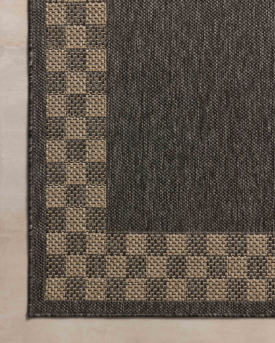 Charcoal grey and tan bordered outdoor rug in modern patio seating area