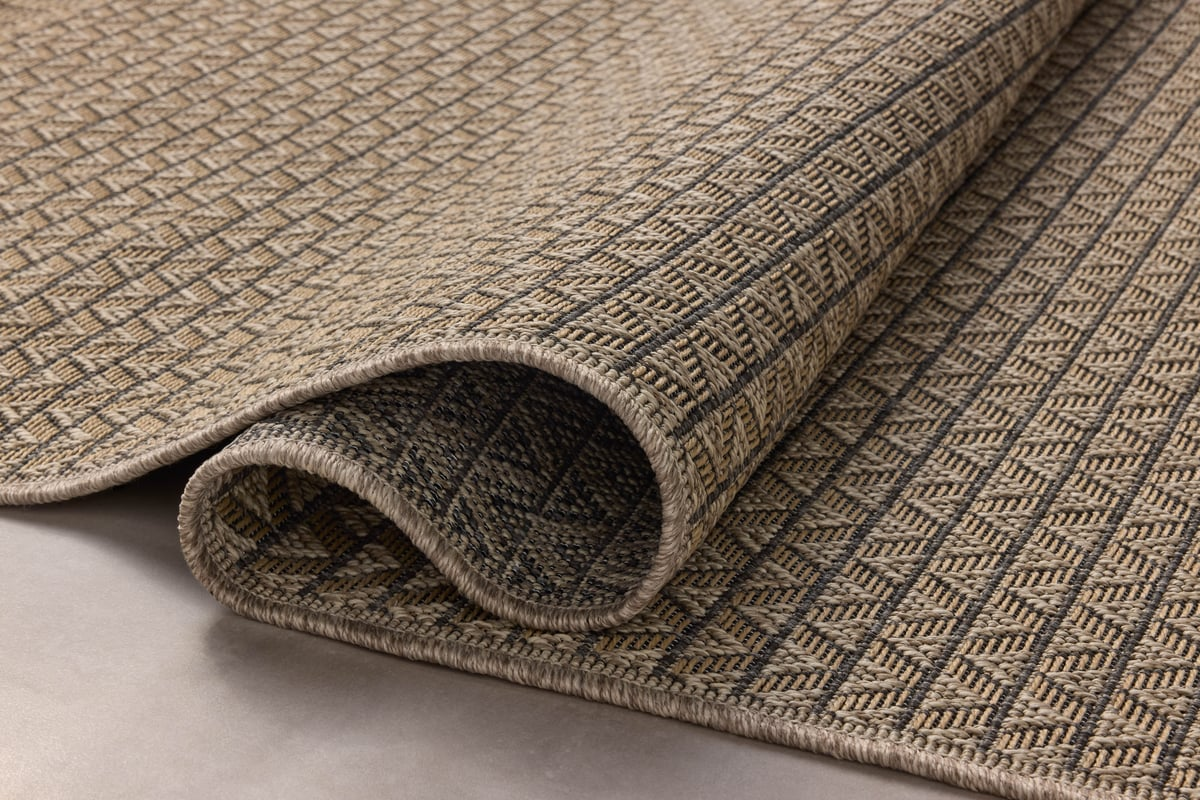 Tan and brown geometric patterned rug with textured weave and striped borders