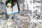 Abstract distressed rug with grey, gold, and cream tones in modern style