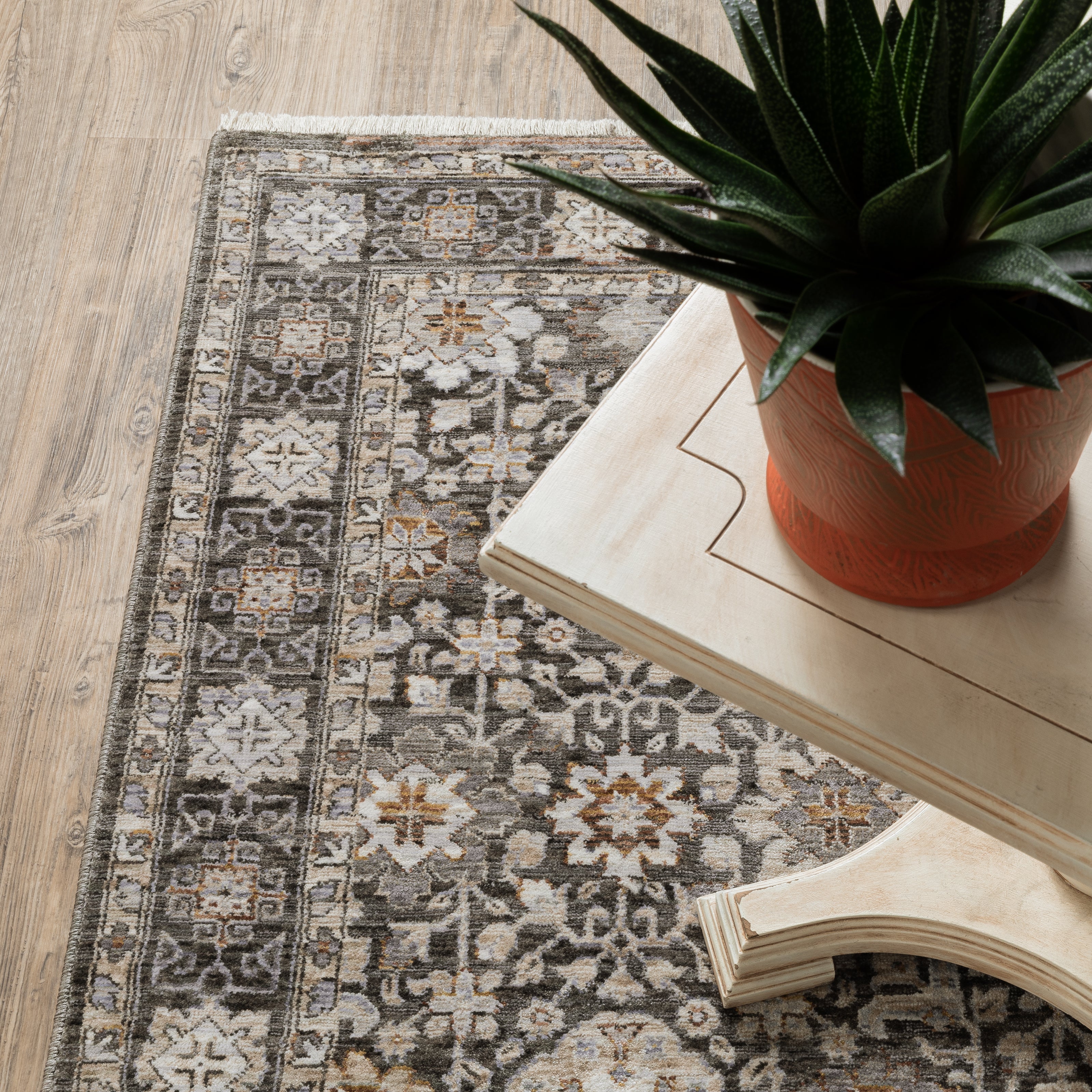 Vintage-style area rug with intricate geometric patterns in beige, taupe and cream tones