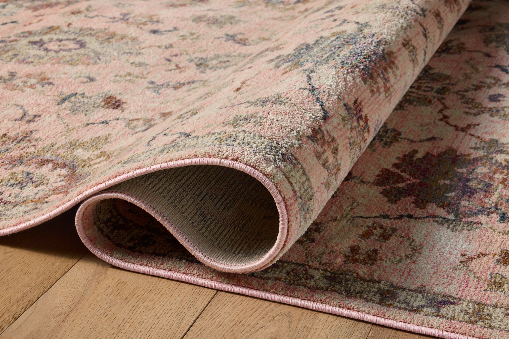 Blush pink traditional rug with intricate floral motifs and ornate border design