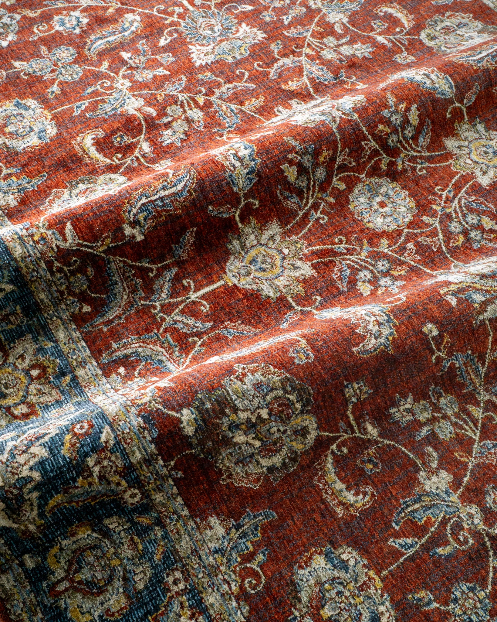 Red traditional rug with ornate floral patterns and blue border design