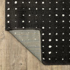 Black wool rug with white polka dot pattern and textured pile surface