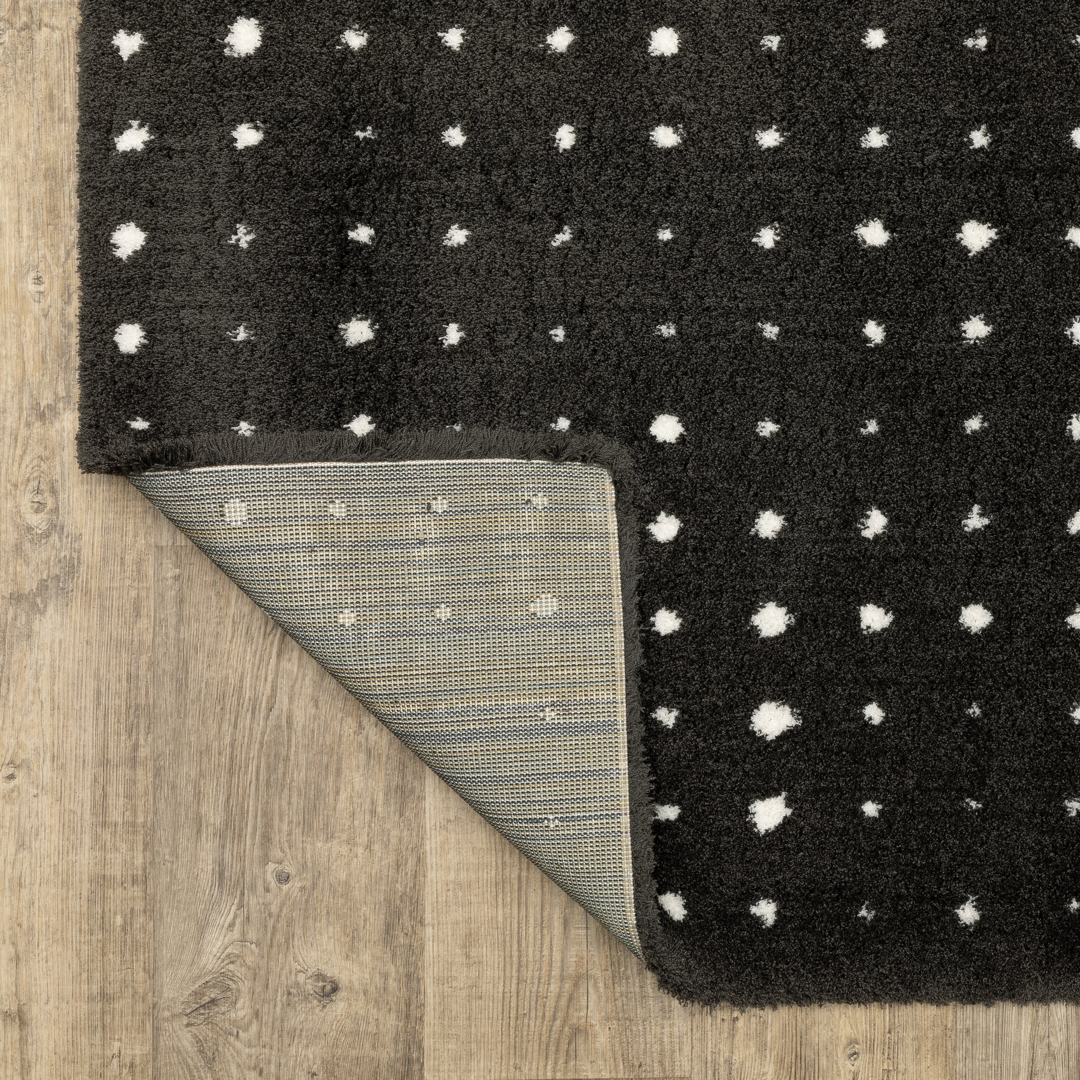 Black wool rug with white polka dot pattern and textured pile surface