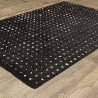 Black wool rug with white polka dot pattern and textured pile surface