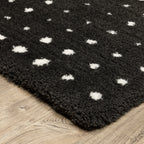 Black wool rug with white polka dot pattern and textured pile surface