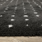 Black wool rug with white polka dot pattern and textured pile surface