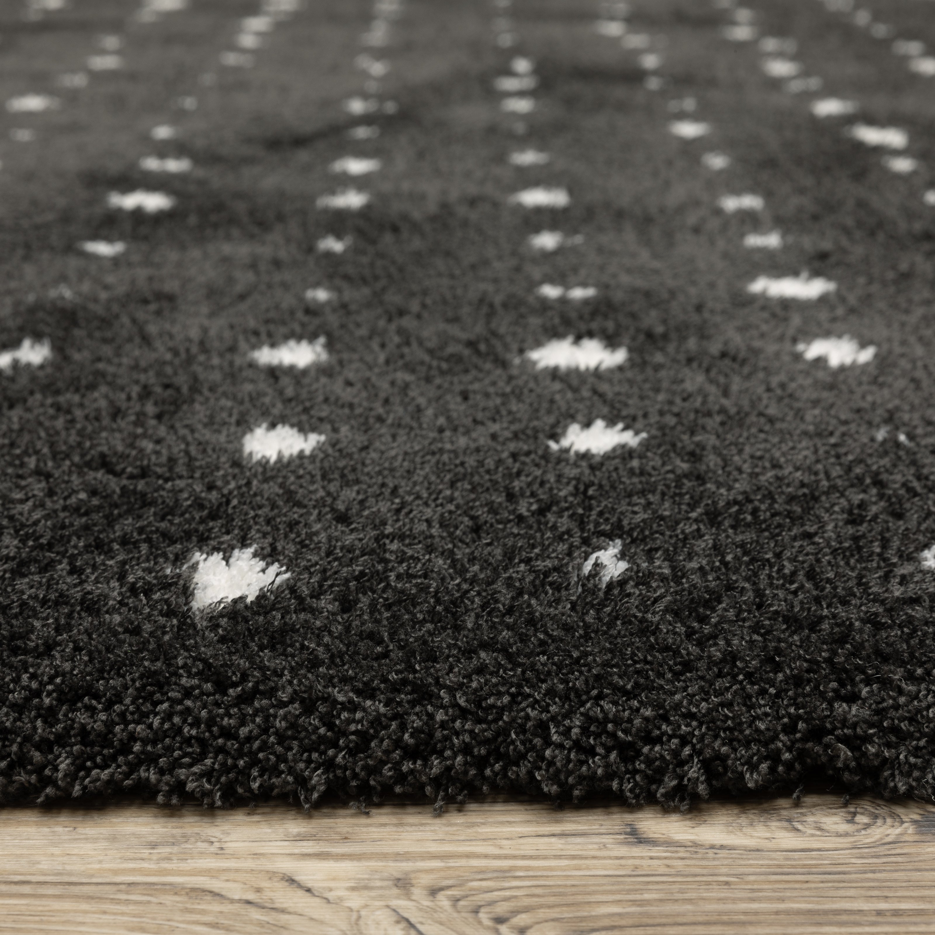 Black wool rug with white polka dot pattern and textured pile surface