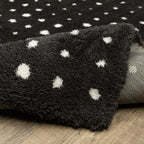Black wool rug with white polka dot pattern and textured pile surface