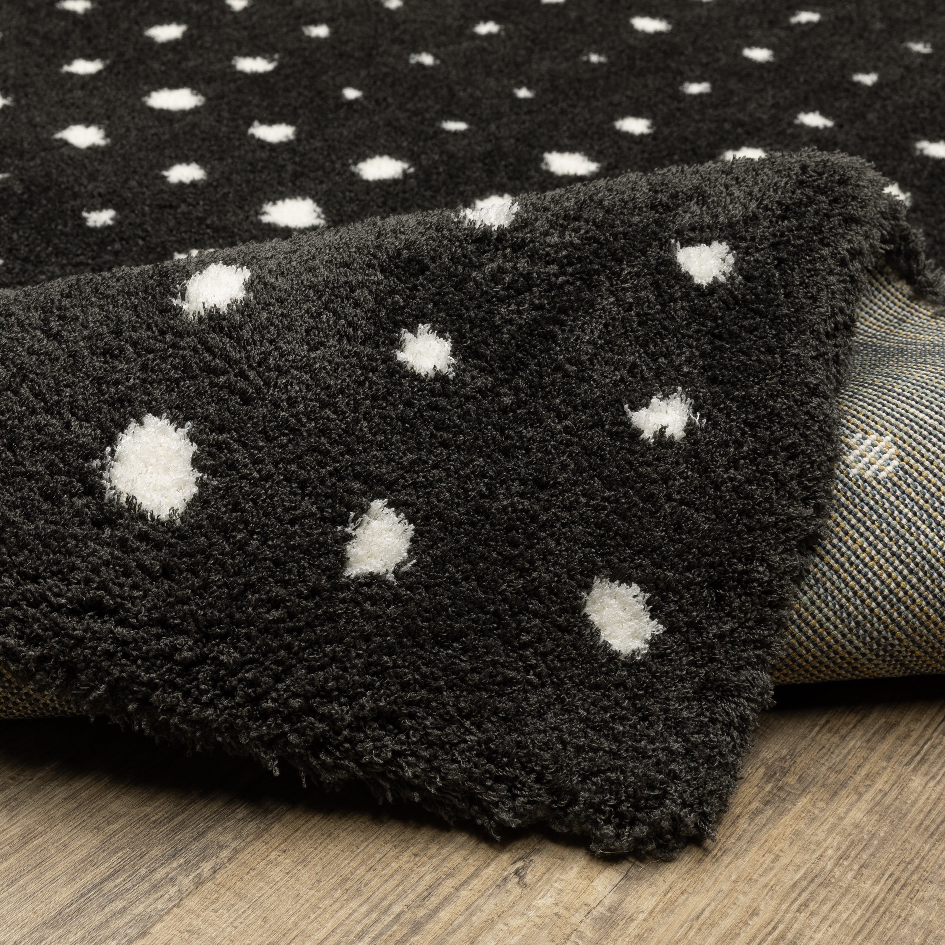 Black wool rug with white polka dot pattern and textured pile surface