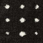 Black wool rug with white polka dot pattern and textured pile surface