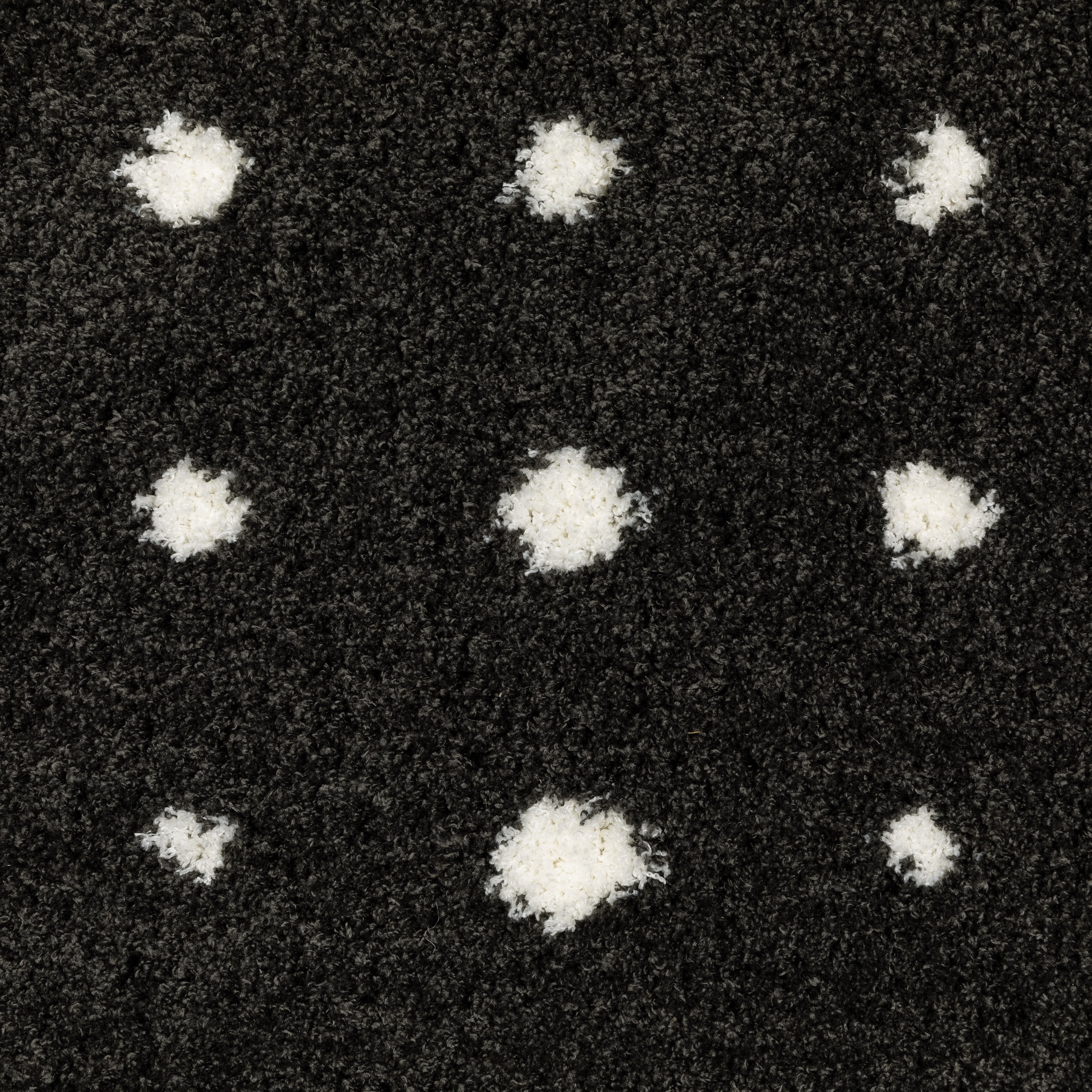 Black wool rug with white polka dot pattern and textured pile surface