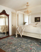 Vintage-style rug with blue-gray base and faded floral pattern in cream and red tones