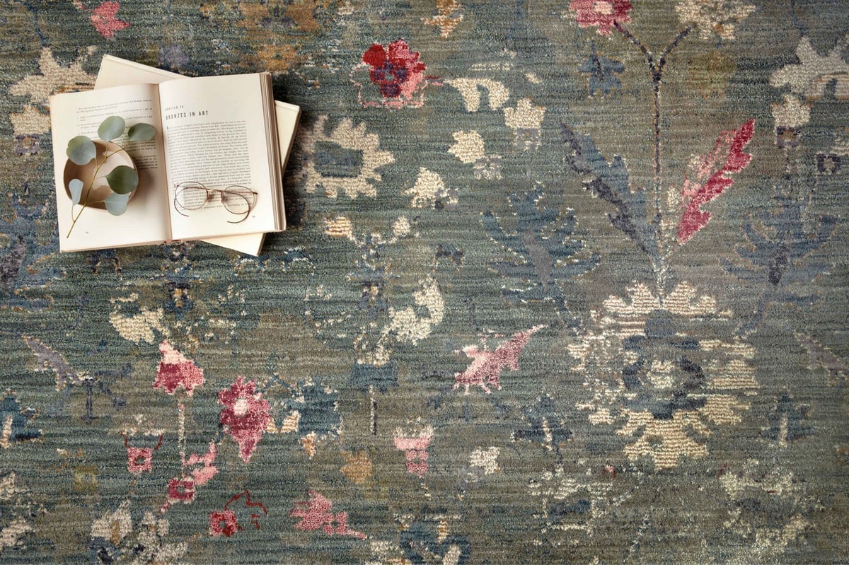 Vintage-style rug with blue-gray base and faded floral pattern in cream and red tones